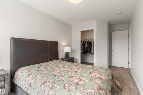 Carpeted bedroom featuring neutral wall tones, a built-in closet with hanging space, a five-panel interior door, and a flush-mount ceiling light - 6003 Edmonds Place Nw, Edmonton, AB - Indoor Photo Showing Bedroom