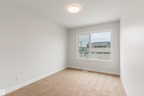 Neutral-toned carpeting extends throughout this room, featuring light gray walls and white trim - 6003 Edmonds Place Nw, Edmonton, AB - Indoor Photo Showing Other Room