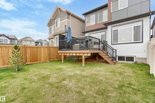 Rear exterior featuring a spacious wooden deck with black metal railings and stairs - 6003 Edmonds Place Nw, Edmonton, AB - Outdoor