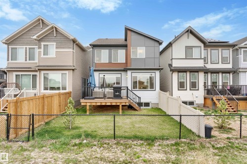 Contemporary rear exterior featuring multi-toned siding, a wooden deck, and a chain-link fence - 6003 Edmonds Place Nw, Edmonton, AB - Outdoor