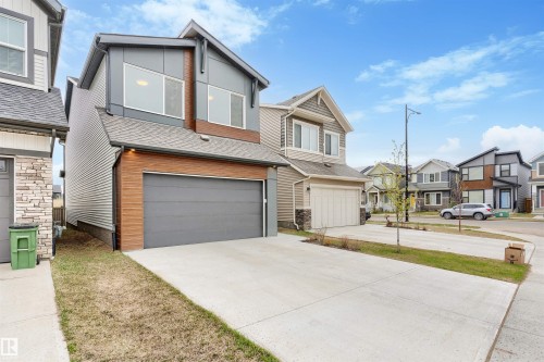 Contemporary two-story residence featuring a gray exterior with wood-finish accents, large windows, and an attached garage - 6003 Edmonds Place Nw, Edmonton, AB - Outdoor