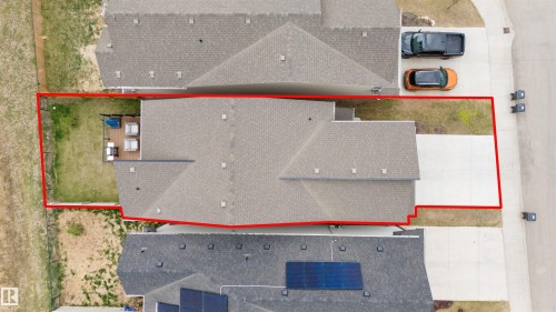 Spacious residential property featuring a gray shingle roof, a two-car concrete driveway, a rear wood-deck patio, and a fenced backyard with grass - 6003 Edmonds Place Nw, Edmonton, AB - 