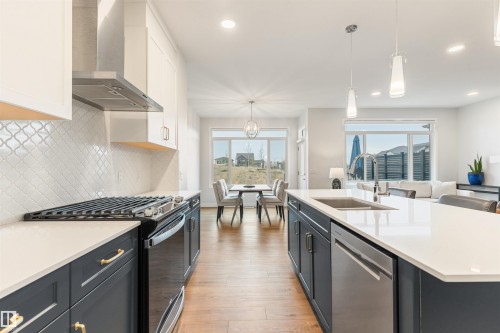 Modern kitchen featuring a gas range, stainless steel appliances, and wood-finish flooring - 6003 Edmonds Place Nw, Edmonton, AB - Indoor Photo Showing Kitchen With Upgraded Kitchen