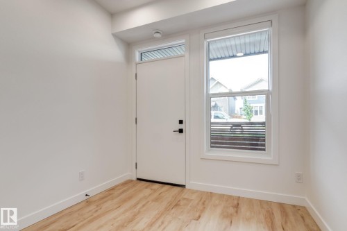 Entryway with wood-finish flooring, white walls, and a white door with black hardware - 16231 19 Avenue, Edmonton, AB - Indoor Photo Showing Other Room