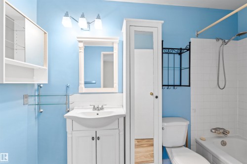 Bathroom with a white vanity sink, white toilet, and white tiled bathtub with shower - 1116 Saddleback Road, Edmonton, AB - Indoor Photo Showing Bathroom