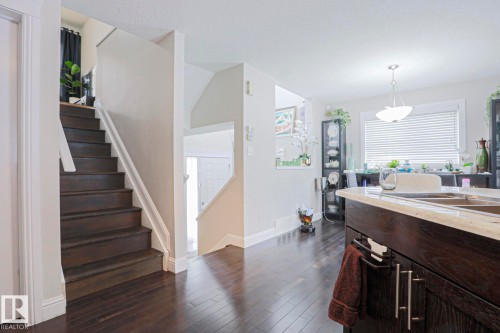 Hardwood-finish flooring throughout, featuring a dark wood staircase with white risers and handrail - 1621 64 Street, Edmonton, AB - Indoor