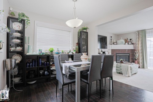 Dining area featuring wood-finish flooring, a contemporary chandelier, and a large window with blinds - 1621 64 Street, Edmonton, AB - Indoor Photo Showing Dining Room With Fireplace