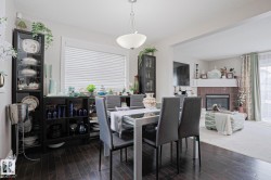 Dining area featuring wood-finish flooring, a contemporary chandelier, and a large window with blinds - 