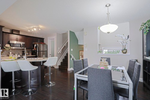 Dining area featuring a contemporary chandelier, dark wood-finish flooring, and a pass-through window to the kitchen - 1621 64 Street, Edmonton, AB - Indoor