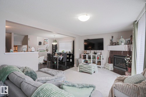 Carpeted living area featuring a built-in fireplace with a tile surround and a mantel - 1621 64 Street, Edmonton, AB - Indoor Photo Showing Living Room With Fireplace
