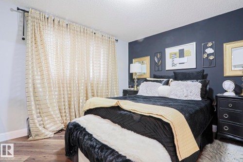 Bedroom featuring a prominent accent wall, wood-finish flooring, and crown molding - 1621 64 Street, Edmonton, AB - Indoor Photo Showing Bedroom