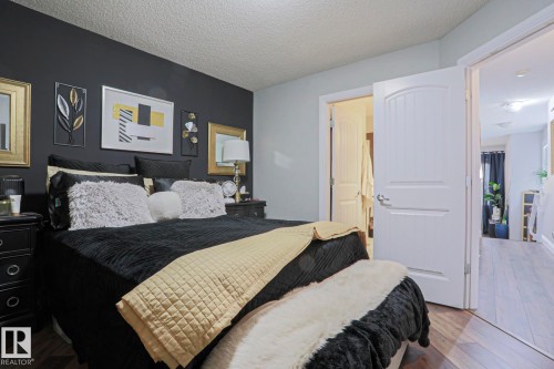 Bedroom featuring a dark accent wall, light grey painted walls, wood-finish flooring, and white interior doors - 1621 64 Street, Edmonton, AB - Indoor Photo Showing Bedroom