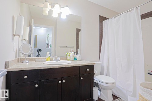 Bathroom featuring a dark wood-finish vanity with a light-colored countertop, an undermount sink, and a large wall-mounted mirror - 1621 64 Street, Edmonton, AB - Indoor Photo Showing Bathroom