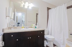 Bathroom featuring a dark wood-finish vanity with a light-colored countertop, an undermount sink, and a large wall-mounted mirror - 