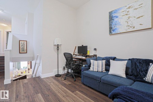 Spacious open area featuring rich wood-finish flooring, white baseboards, and a contemporary light gray wall color - 1621 64 Street, Edmonton, AB - Indoor