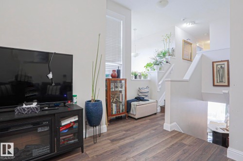 Wood-finish flooring throughout, featuring a staircase with white risers and handrails, an upper landing with natural light, and a built-in display cabinet - 1621 64 Street, Edmonton, AB - Indoor Photo Showing Other Room