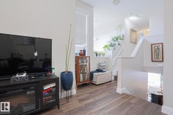 Wood-finish flooring throughout, featuring a staircase with white risers and handrails, an upper landing with natural light, and a built-in display cabinet - 