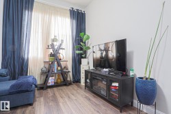 Spacious interior featuring wood-finish flooring, light-toned walls, and a large window with privacy sheers and opaque drapery panels - 