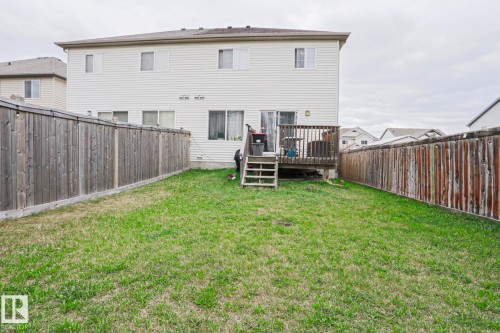 Expansive rear yard featuring a wooden privacy fence, verdant lawn, and a raised wooden deck with stairs to the yard - 1621 64 Street, Edmonton, AB - Outdoor With Deck Patio Veranda With Exterior