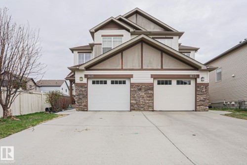 Contemporary facade featuring light-colored siding, a stone veneer accent, and a dual garage - 1621 64 Street, Edmonton, AB - Outdoor