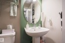 Pedestal sink with chrome faucet, complemented by an oval mirror and two-tone wall finishes - 1621 64 Street, Edmonton, AB  - Indoor Photo Showing Bathroom 