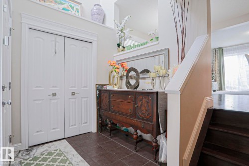 Entryway featuring bi-fold doors, dark-toned flooring, and a staircase with dark wood-finish treads and a white painted banister - 1621 64 Street, Edmonton, AB - Indoor Photo Showing Other Room