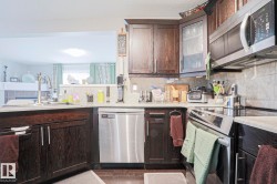 Kitchen featuring dark wood-finish cabinetry, stainless steel appliances, a tile backsplash, and light-toned countertops - 