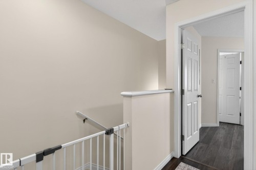 Hallway featuring wood-finish flooring, light-colored walls, white trim, and white paneled doors - 16 7503 Getty Gate, Edmonton, AB - Indoor Photo Showing Other Room