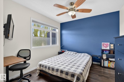 Bedroom featuring wood-finish flooring, a ceiling fan with light fixture, and a large window with frosted lower panes - 16 7503 Getty Gate, Edmonton, AB - Indoor Photo Showing Bedroom