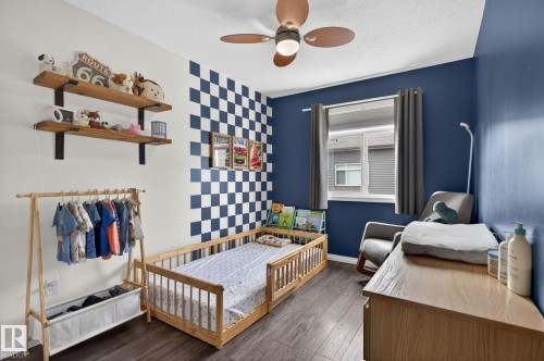 Room featuring wood-finish flooring, a ceiling fan with integrated lighting, and a single window with blinds and drapes - 16 7503 Getty Gate, Edmonton, AB - Indoor Photo Showing Bedroom