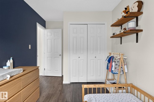 Room featuring wood-finish flooring, a neutral wall color, and an accent wall - 16 7503 Getty Gate, Edmonton, AB - Indoor Photo Showing Bedroom