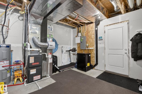 Utility room featuring a water heater, furnace, and exposed ceiling joists - 16 7503 Getty Gate, Edmonton, AB - Indoor Photo Showing Basement