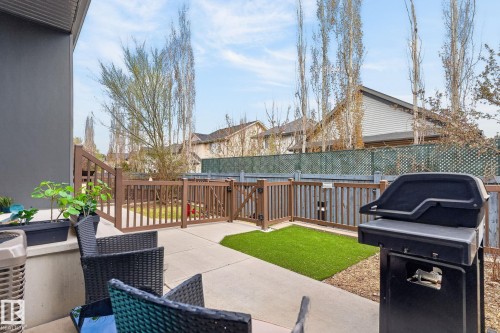 Paved patio area featuring a brown privacy fence, artificial turf section, and a gate - 16 7503 Getty Gate, Edmonton, AB - Outdoor With Exterior