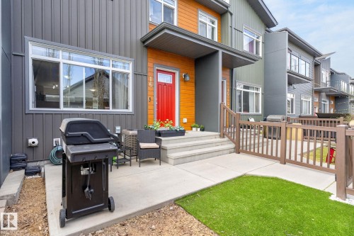 Contemporary townhome exterior featuring grey vertical siding and wood-finish accent panels - 16 7503 Getty Gate, Edmonton, AB - Outdoor