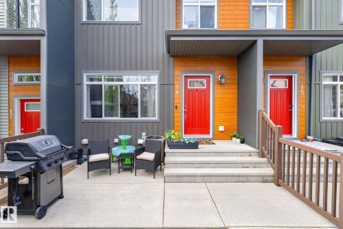 Modern townhome exterior with contrasting vertical siding and horizontal wood-finish accents - 16 7503 Getty Gate, Edmonton, AB - Outdoor With Exterior