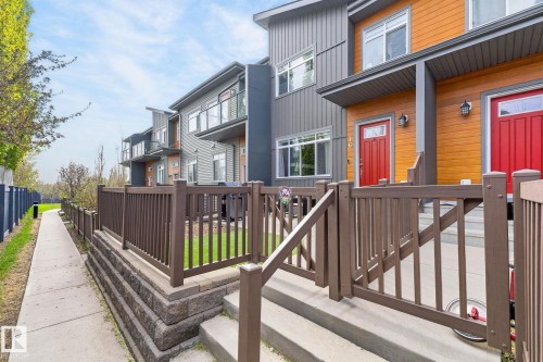 Contemporary townhome exterior featuring an orange and gray facade with red entry doors - 16 7503 Getty Gate, Edmonton, AB - Outdoor With Exterior