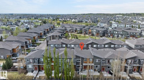 Contemporary townhome with a dark gray exterior, light wood-tone accents, and a contrasting red entry door - 16 7503 Getty Gate, Edmonton, AB - Outdoor
