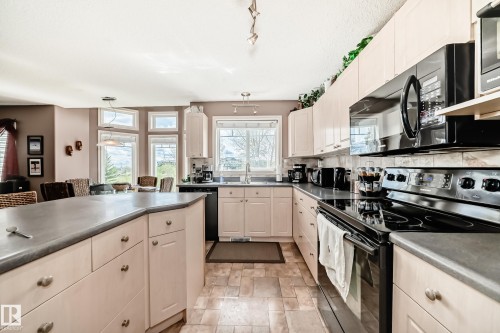 Spacious kitchen featuring light wood-finish cabinetry,  a large island with counter seating. - 5107 200 Street, Edmonton, AB - Indoor Photo Showing Kitchen