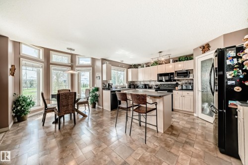 Kitchen featuring light-toned cabinetry, a central island with bar seating. - 5107 200 Street, Edmonton, AB - Indoor