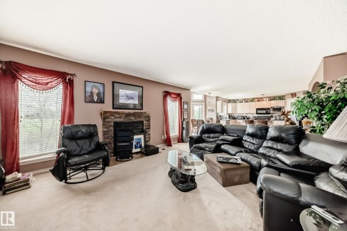 Living area featuring a brick faced fireplace and broad windows - 5107 200 Street, Edmonton, AB - Indoor Photo Showing Living Room