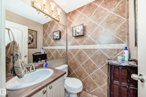 Bathroom featuring a vanity with an integrated sink, a rectangular mirror, and a three-light fixture - 5107 200 Street, Edmonton, AB - Indoor Photo Showing Bathroom