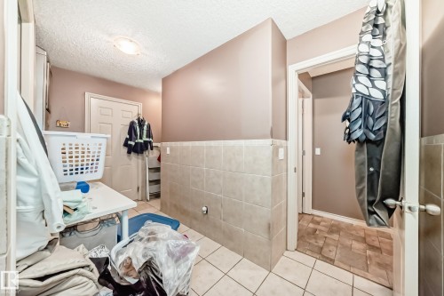 Utility room featuring a ceramic tile floor, partial wall tiling, and a flush-mount ceiling light - 5107 200 Street, Edmonton, AB - Indoor Photo Showing Other Room