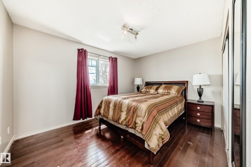 Bedroom featuring dark wood-finish flooring, light-toned walls, and a window with a white frame - 5107 200 Street, Edmonton, AB - Indoor Photo Showing Bedroom