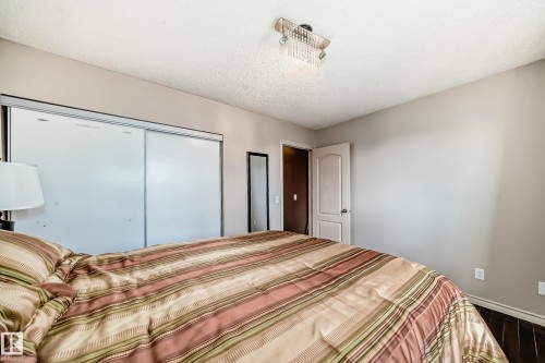 Bedroom featuring light gray wall paint, dark wood-finish flooring, and a crystal flush mount ceiling fixture - 5107 200 Street, Edmonton, AB - Indoor Photo Showing Bedroom