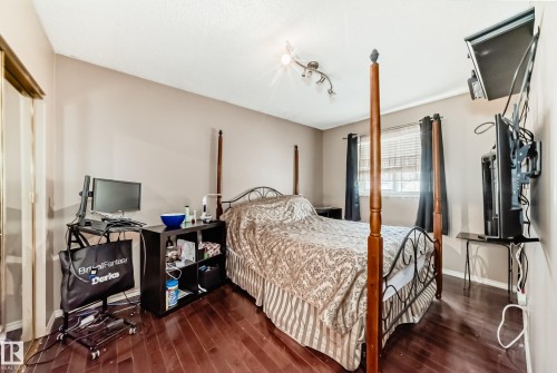 Spacious room featuring wood-finish flooring, neutral wall tones, and track lighting - 5107 200 Street, Edmonton, AB - Indoor Photo Showing Bedroom