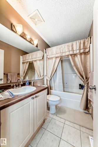 Full bathroom featuring a single vanity with under-sink cabinetry, a built-in tub with shower, and tile flooring - 5107 200 Street, Edmonton, AB - Indoor Photo Showing Bathroom