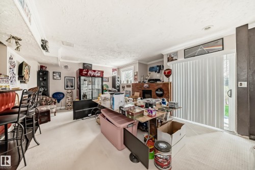 Spacious interior room featuring light-toned carpeting, crown molding, and a sliding glass door providing exterior access - 5107 200 Street, Edmonton, AB - Indoor