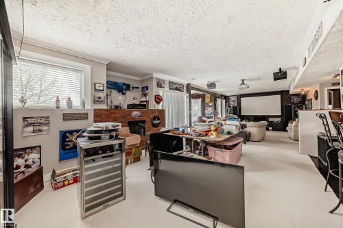 Spacious lower level featuring a large projection screen, recessed lighting, and a built-in brick electric fireplace - 5107 200 Street, Edmonton, AB - Indoor