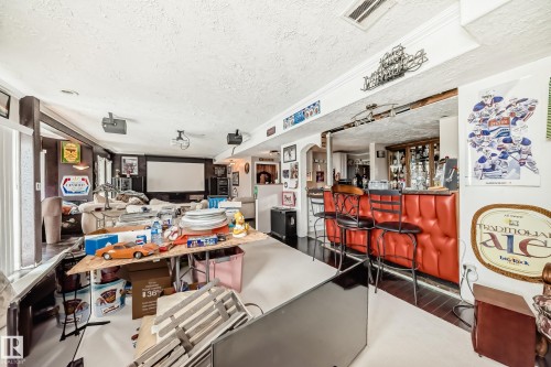 Recreational room featuring a built-in wet bar with red upholstered siding, dark wood-finish flooring, and a large projection screen - 5107 200 Street, Edmonton, AB - Indoor