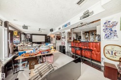 Recreational room featuring a built-in wet bar with red upholstered siding, dark wood-finish flooring, and a large projection screen - 